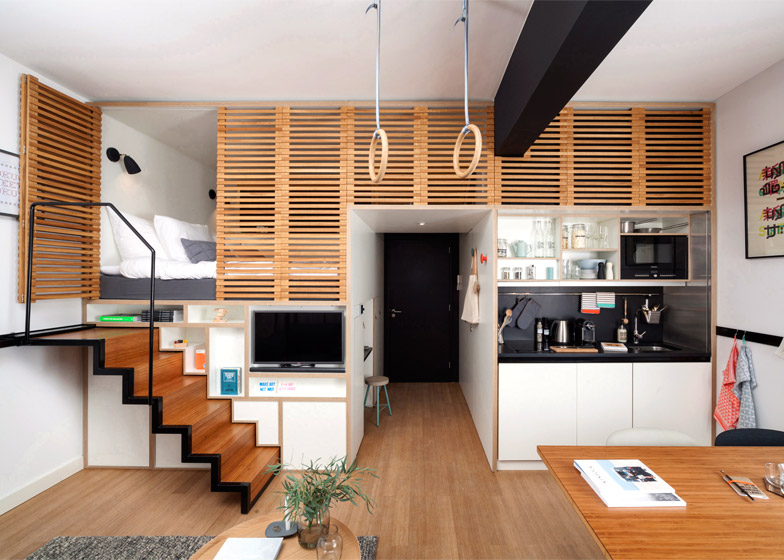 A compact loft with a stair to a raised bed platform above a work table