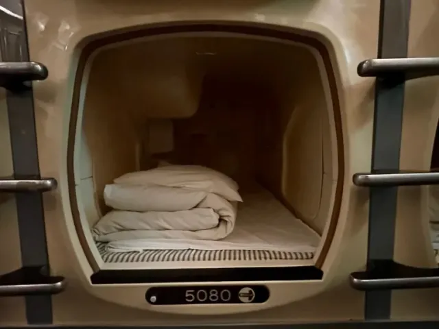 A shared lounge floor beneath rows of compact sleeping berths