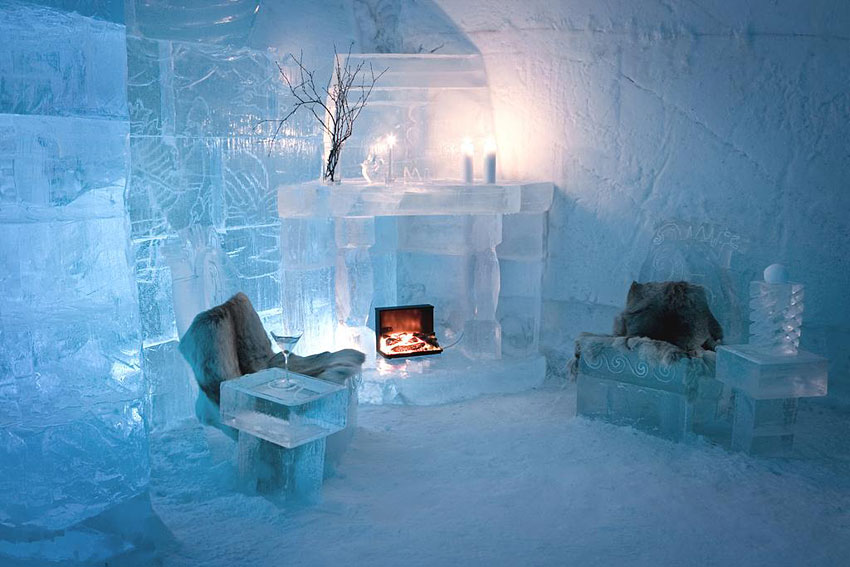 A packed snow corridor with arched walls leading to a lit chamber